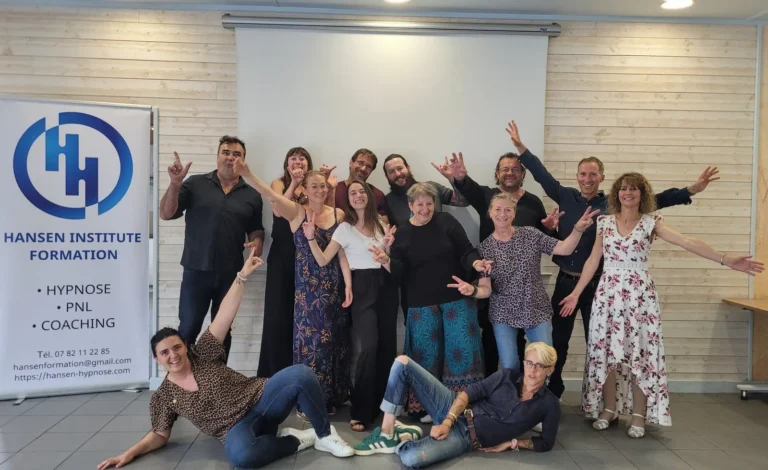 Groupe joyeux de nouveaux praticiens en hypnose posant bras levés en fin de formation